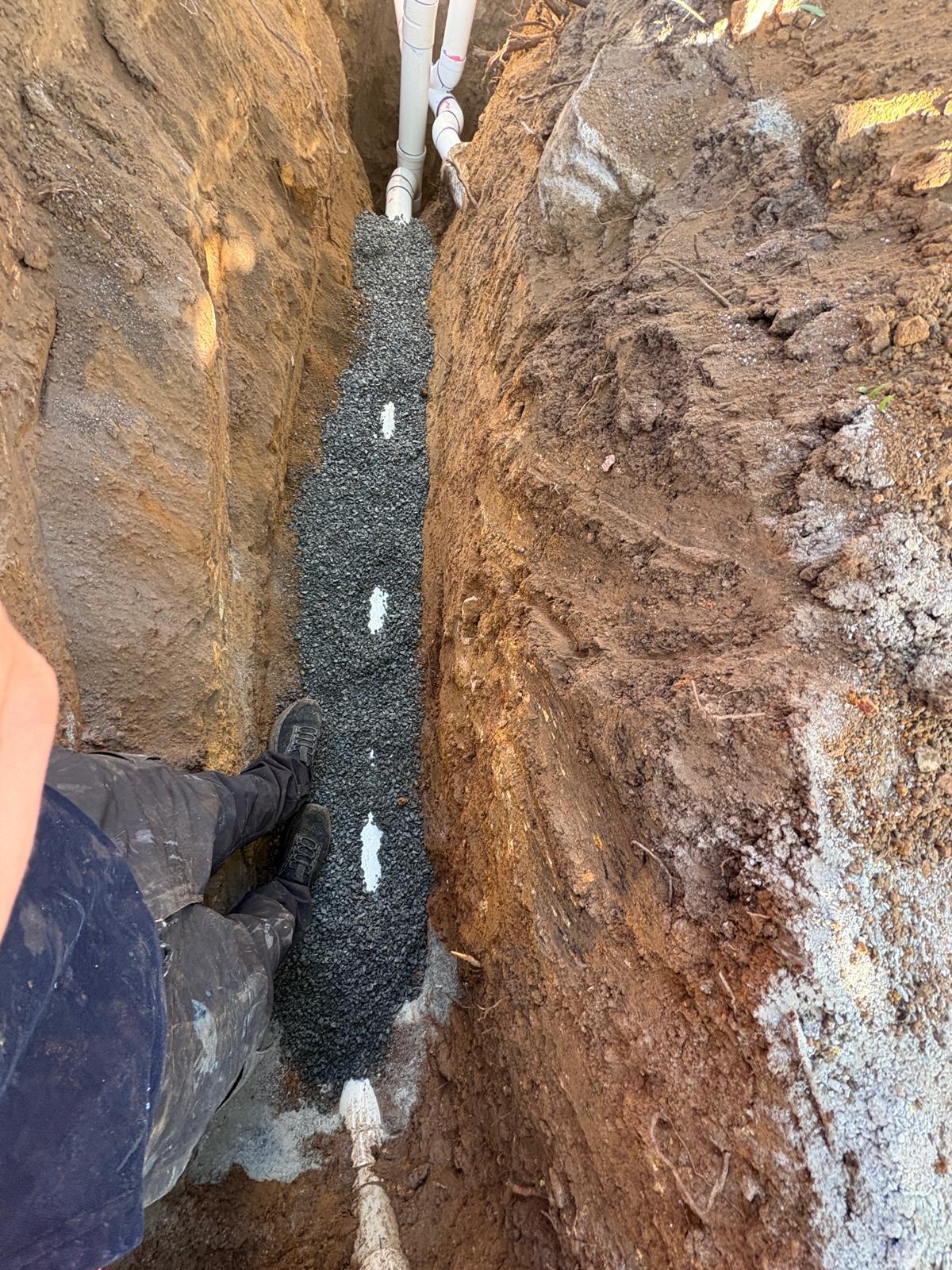 New PVC sewer line laid on a compacted gravel bed in a deep Canberra trench