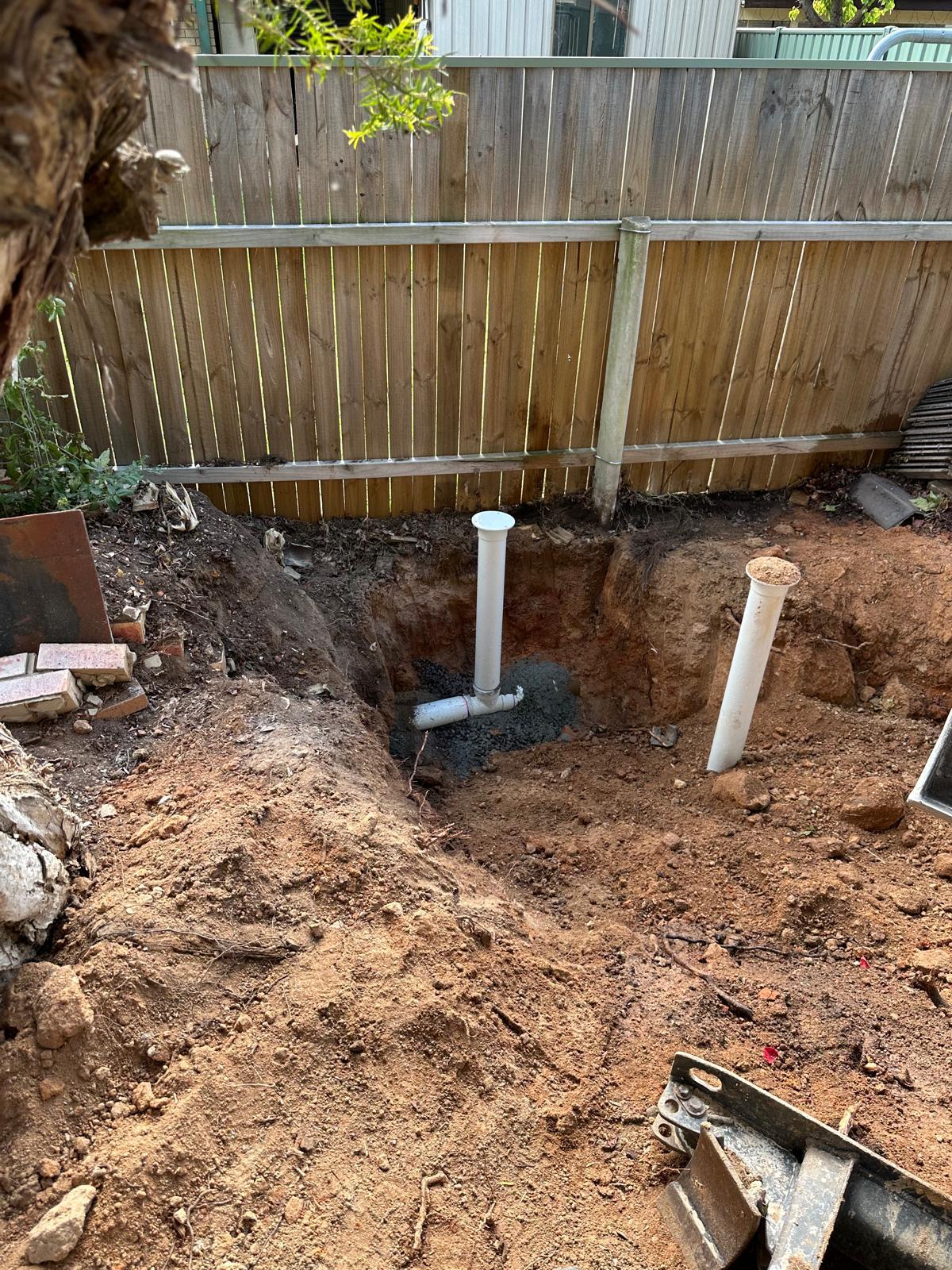 Two new drainage risers set in concrete during a Canberra backyard drain repair